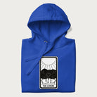 Folded royal blue hoodie with a 'The Lovers' tarot card graphic of two cats with intertwined tails forming a heart, wine, and roses.