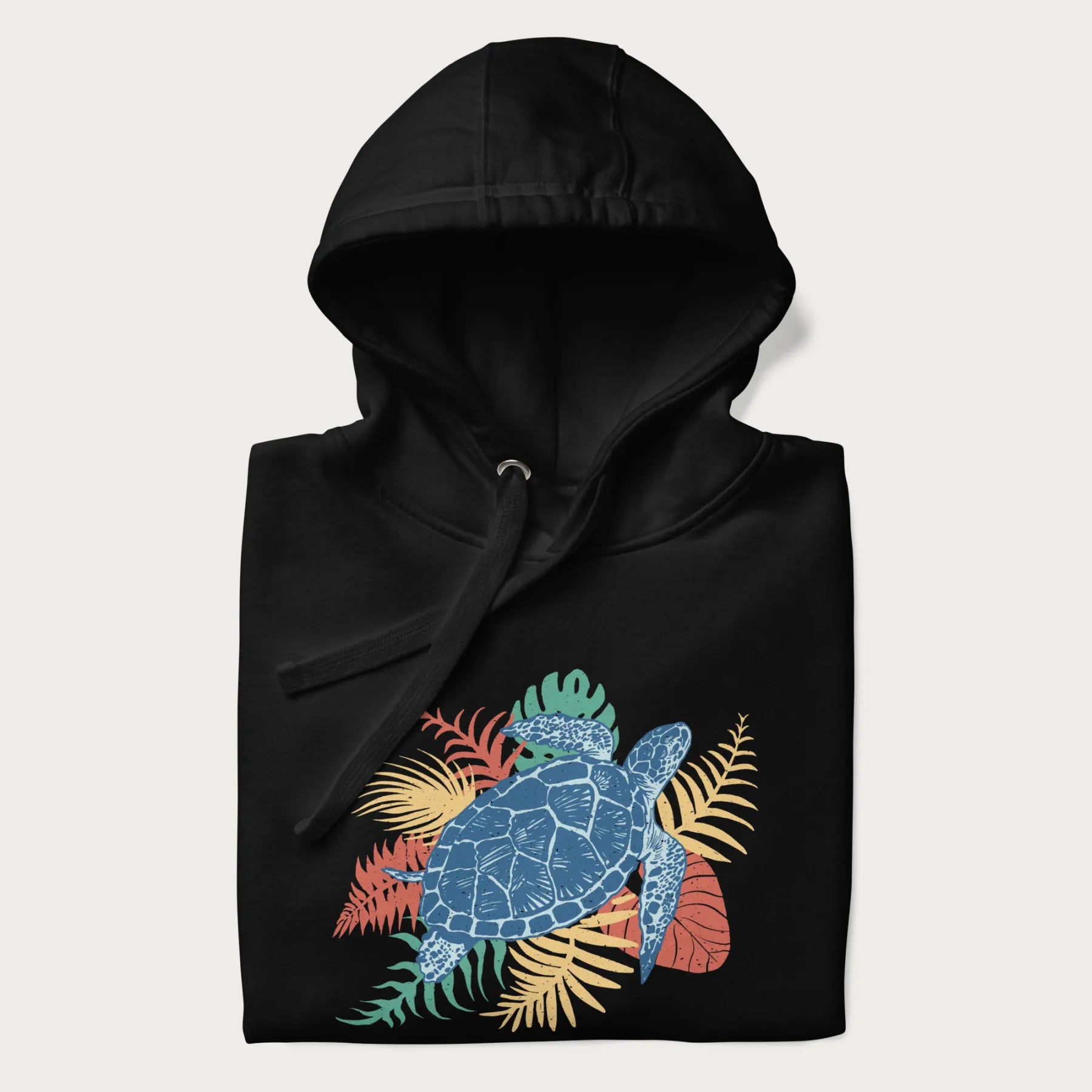 Folded black hoodie with a vibrant graphic of a blue sea turtle and colorful tropical leaves.