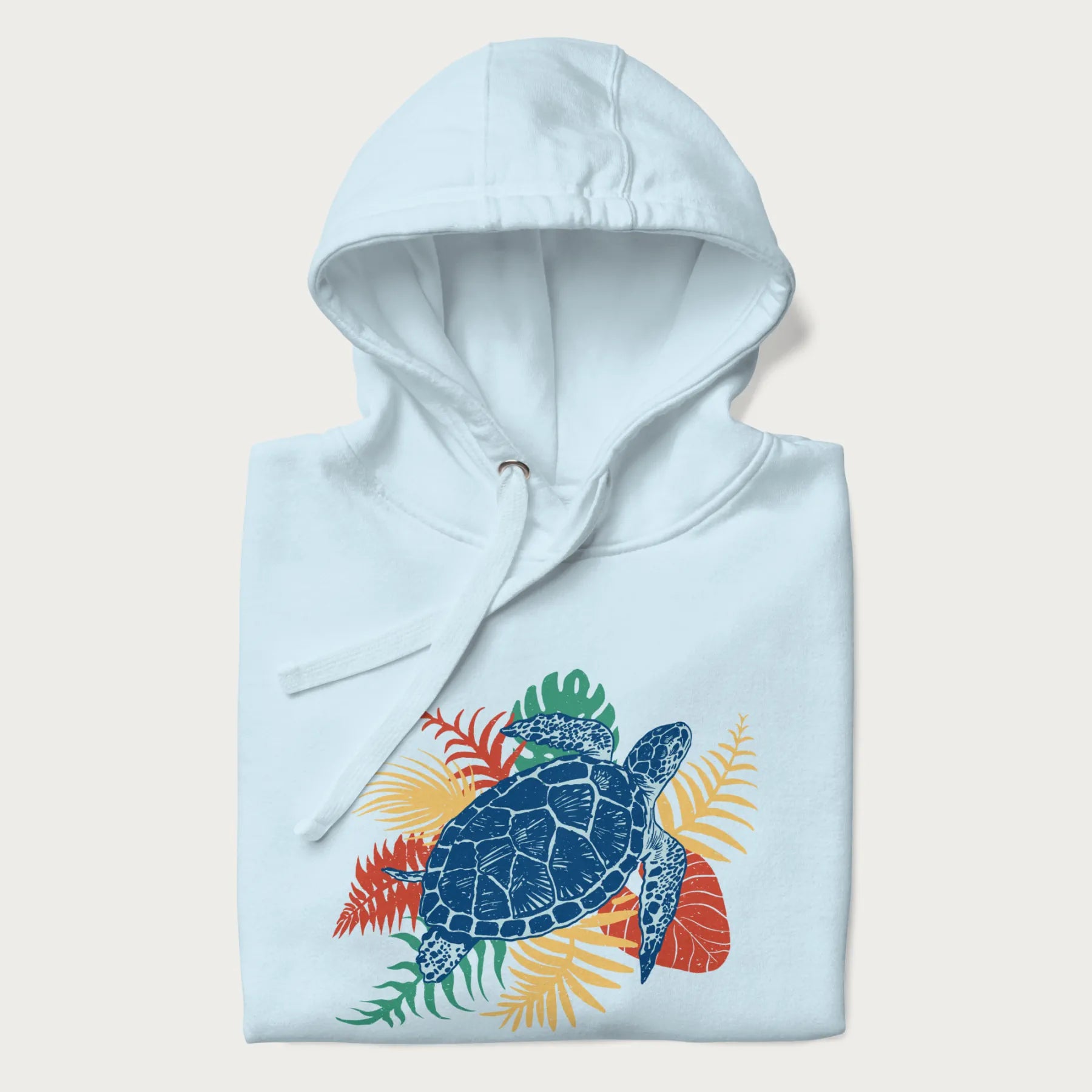 Folded light blue hoodie with a vibrant graphic of a blue sea turtle and colorful tropical leaves.