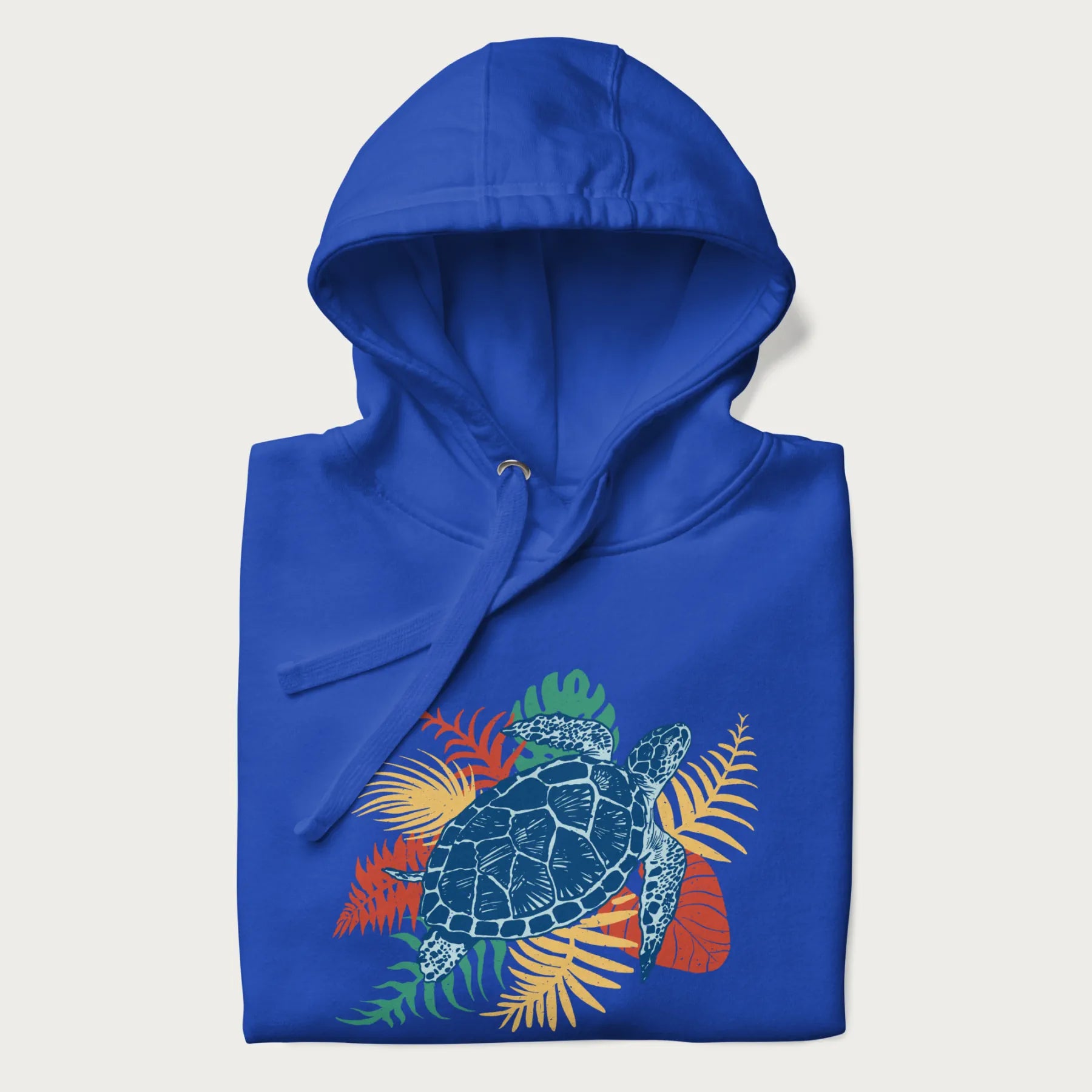 Folded royal blue hoodie with a vibrant graphic of a blue sea turtle and colorful tropical leaves.