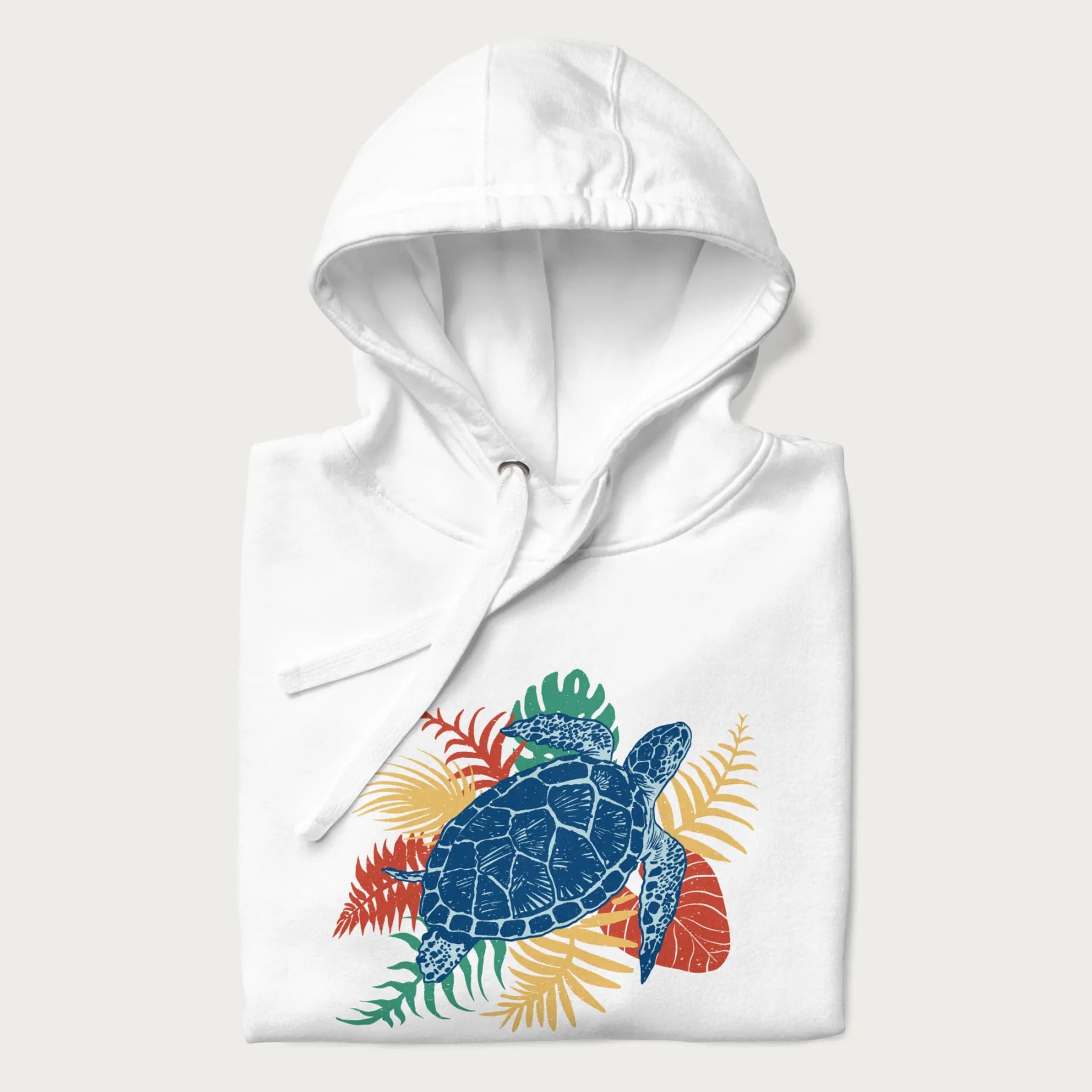 Folded white hoodie with a vibrant graphic of a blue sea turtle and colorful tropical leaves.