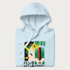 Folded light blue hoodie with Japanese text and a graphic of a retro-futuristic robot fighter, inspired by Japanese mecha art.