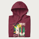 Folded maroon hoodie with Japanese text and a graphic of a retro-futuristic robot fighter, inspired by Japanese mecha art.