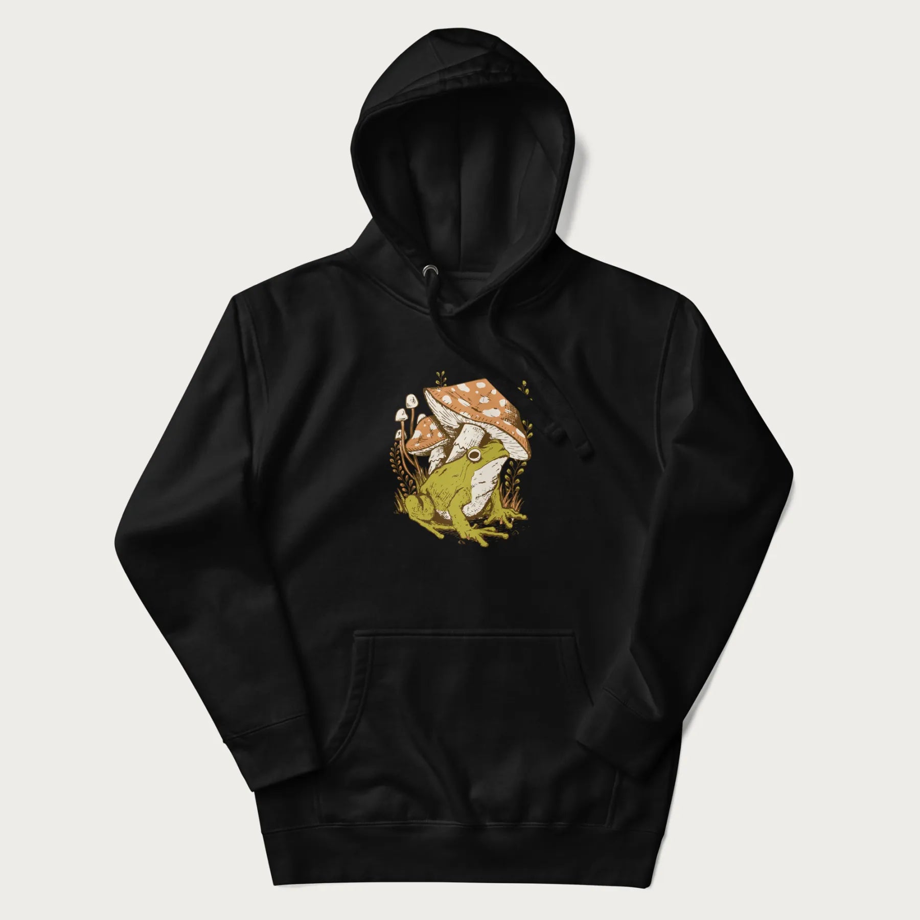 Black hoodie with cottagecore graphic of a frog under mushrooms with foliage in the background.