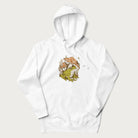 White hoodie with cottagecore graphic of a frog under mushrooms with foliage in the background.