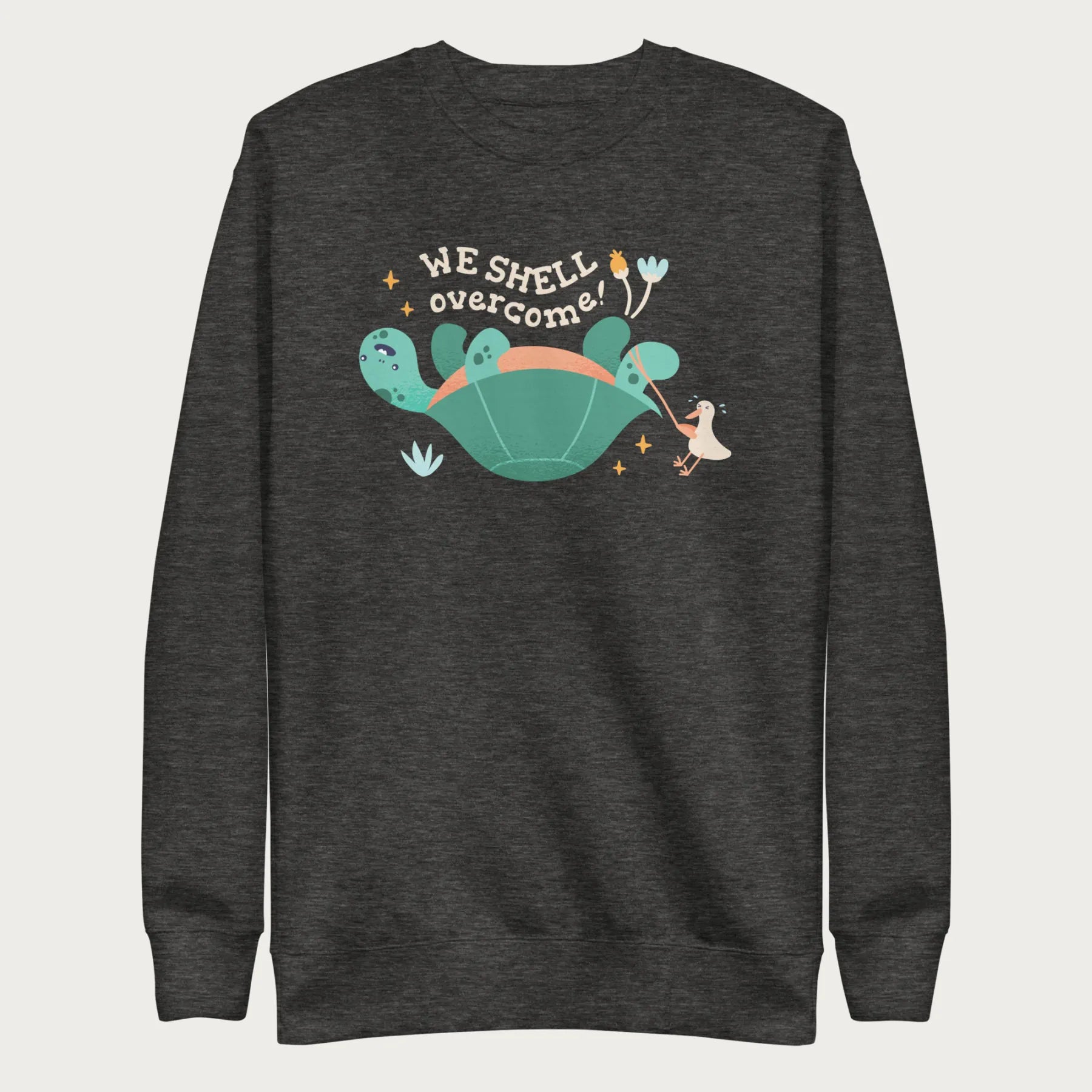 Dark grey sweatshirt with a graphic of a turtle flipped on it's shell with the phrase 'We Shell Overcome.'