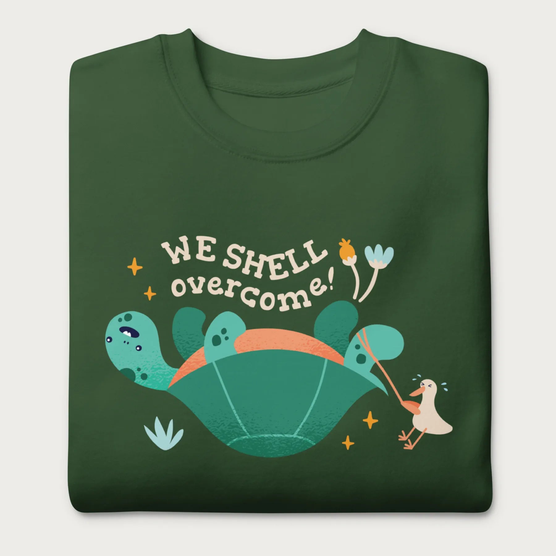 Folded forest green sweatshirt with a graphic of a turtle flipped on it's shell with the phrase 'We Shell Overcome.'