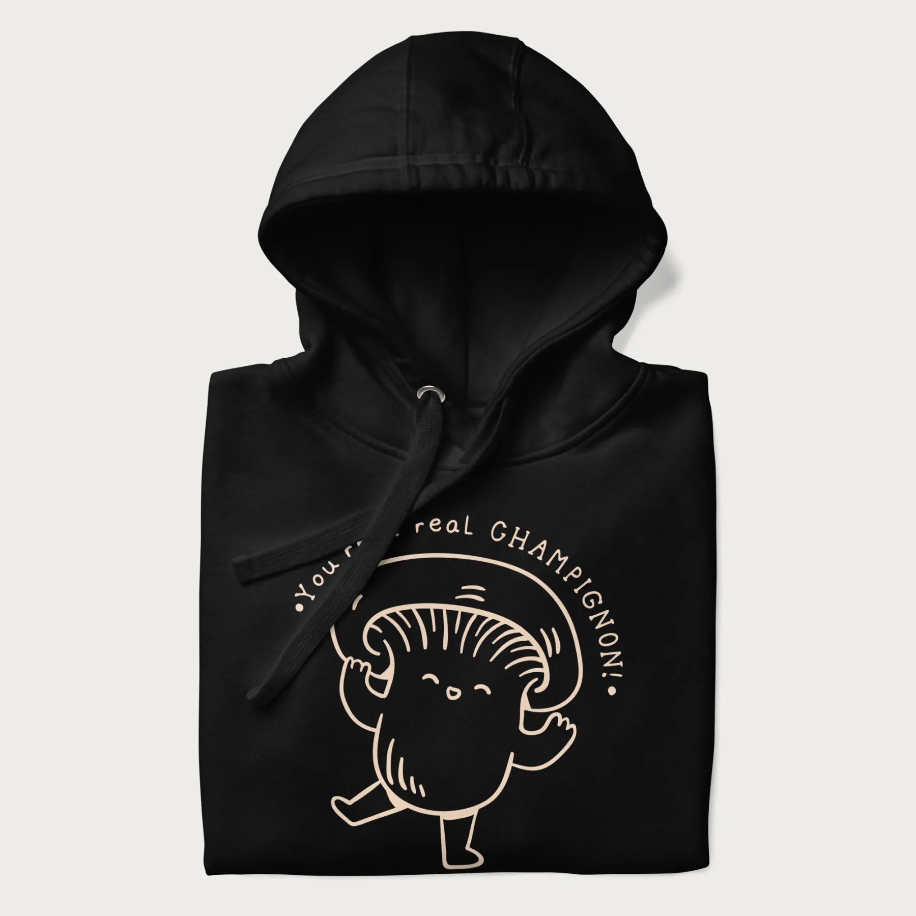 Folded black hoodie with a cute champignon mushroom graphic and the text "You're a Real Champignon!"