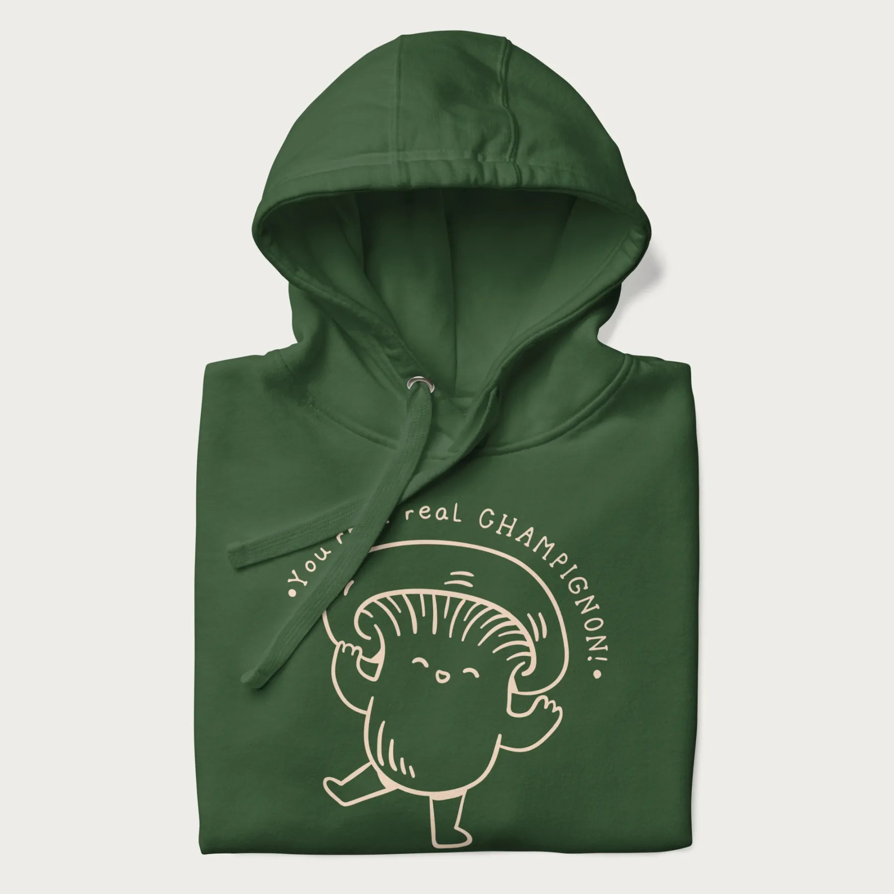 Folded forest green hoodie with a cute champignon mushroom graphic and the text "You're a Real Champignon!"