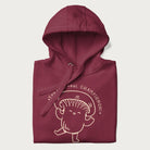 Folded maroon hoodie with a cute champignon mushroom graphic and the text "You're a Real Champignon!"