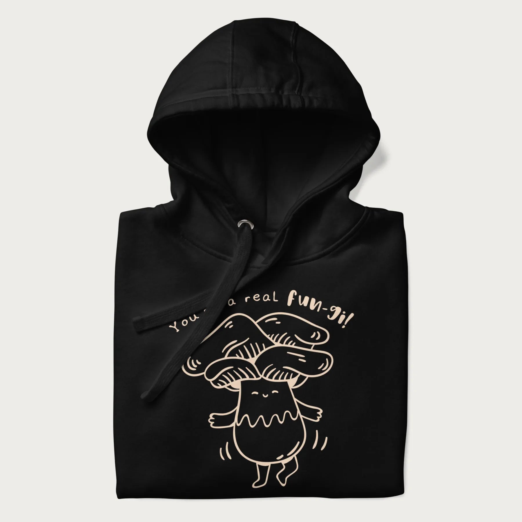 Folded black hoodie with graphic of a cute mushroom joyfully dancing with the text "You're a Real Fun-gi!"