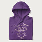 Folded purple hoodie with graphic of a cute mushroom joyfully dancing with the text "You're a Real Fun-gi!"