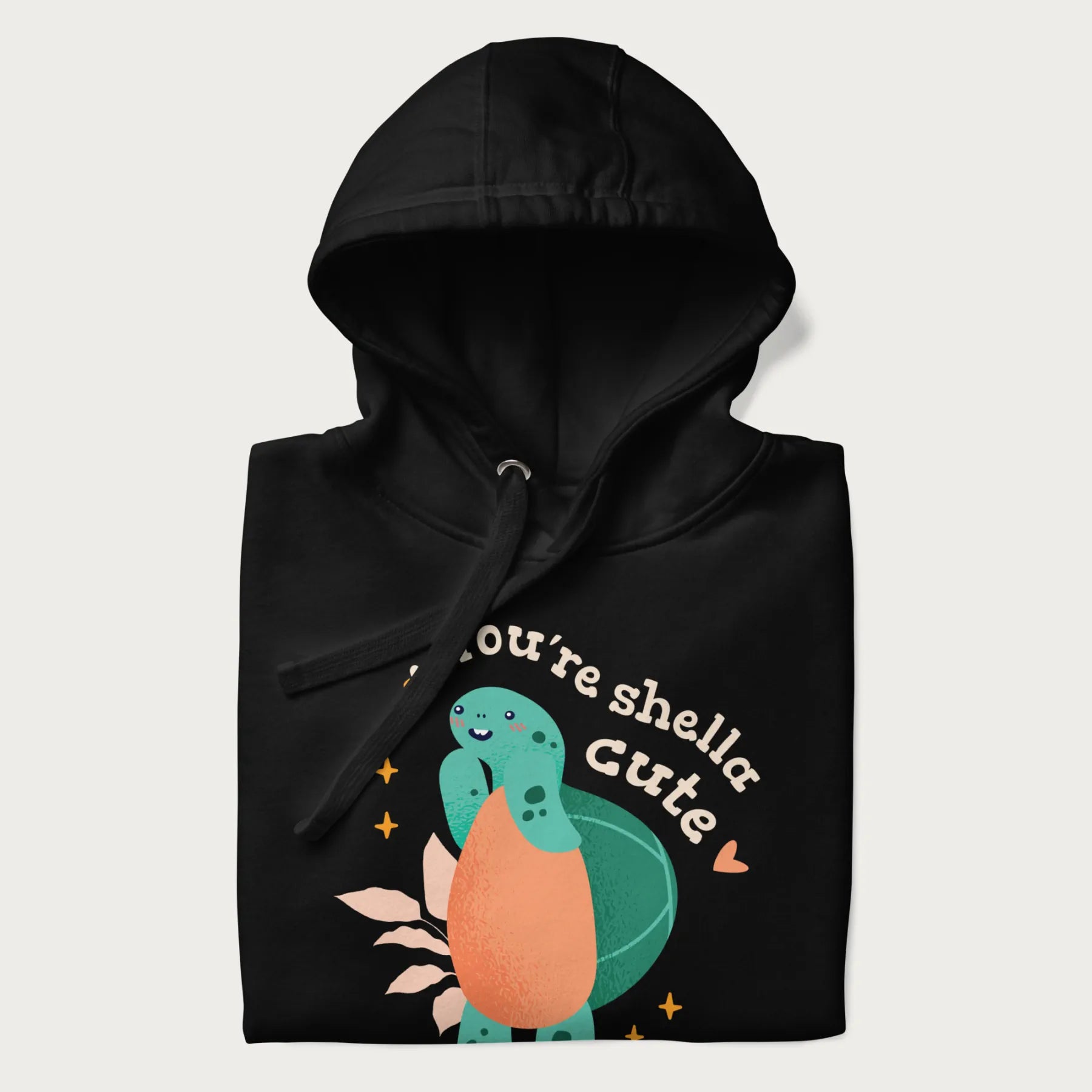 Folded black hoodie with a cute turtle graphic and the text 'You're Shella Cute' above.