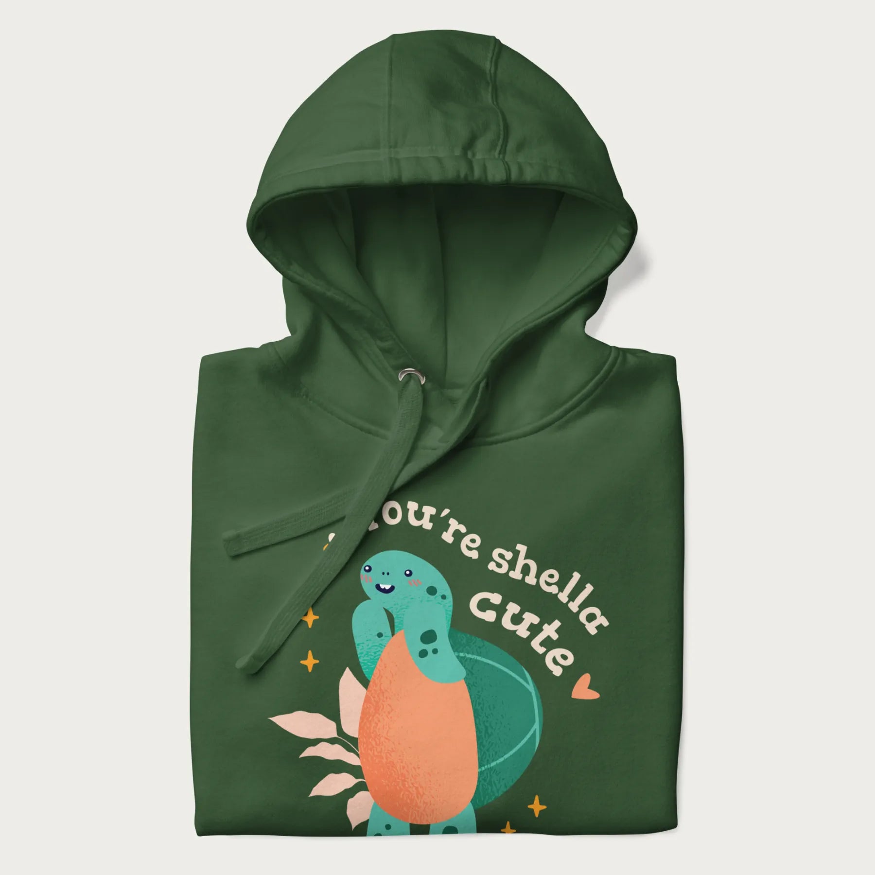 Folded forest green hoodie with a cute turtle graphic and the text 'You're Shella Cute' above.