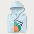 Folded light blue hoodie with a cute turtle graphic and the text 'You're Shella Cute' above.