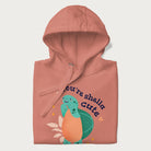 Folded light pink hoodie with a cute turtle graphic and the text 'You're Shella Cute' above.