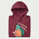 Folded maroon hoodie with a cute turtle graphic and the text 'You're Shella Cute' above.