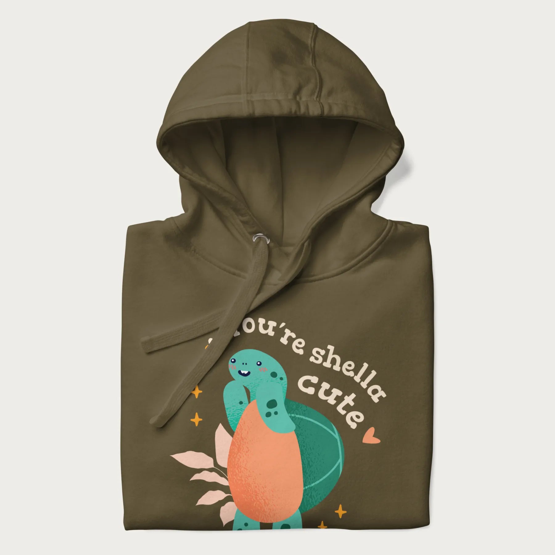 Folded military green hoodie with a cute turtle graphic and the text 'You're Shella Cute' above.