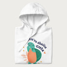 Folded white hoodie with a cute turtle graphic and the text 'You're Shella Cute' above.